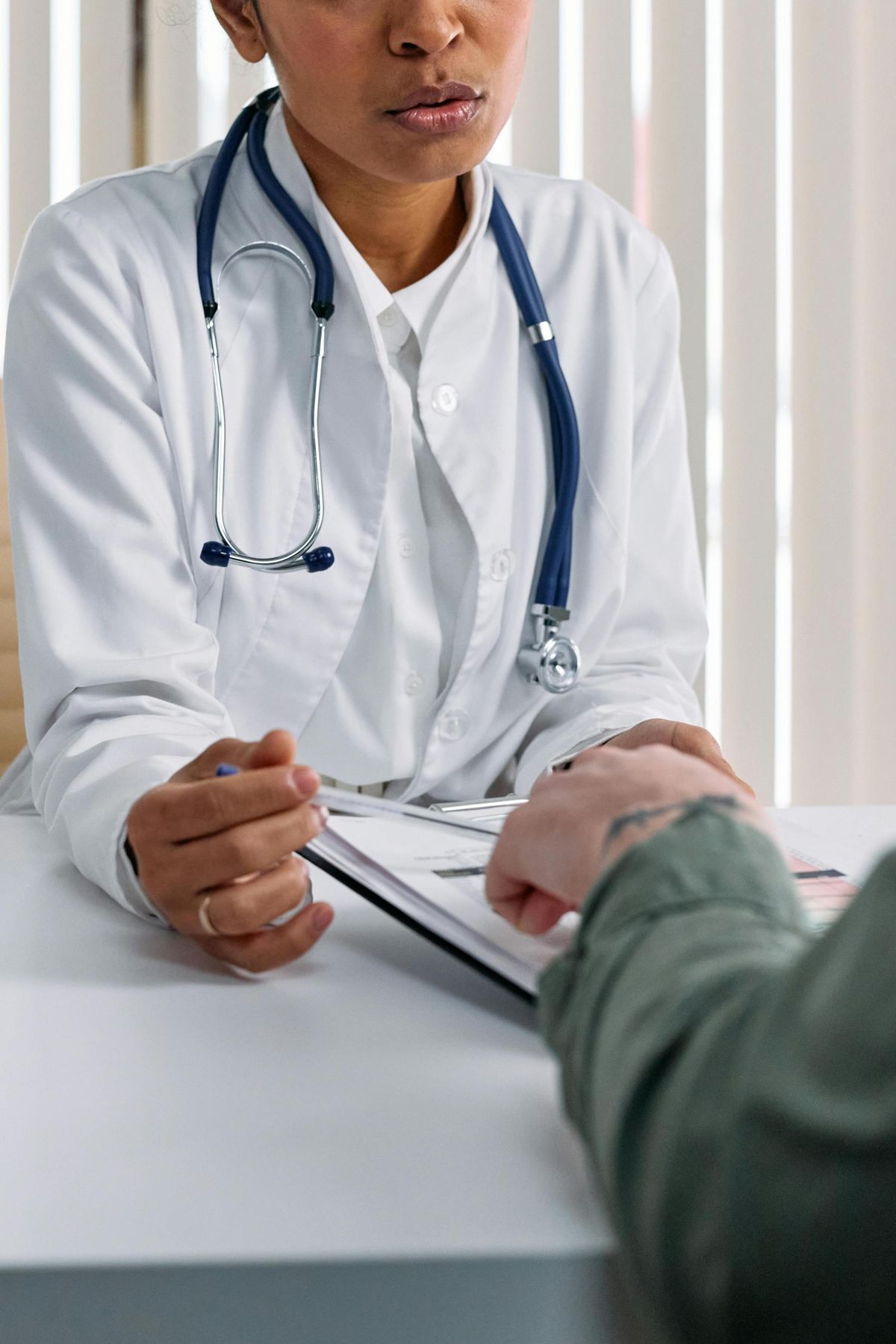 A doctor talks a patient through paperwork at a clinic desk