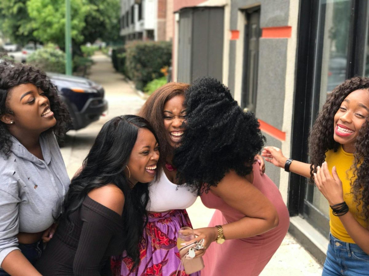 Friends laughing together on a sunny sidewalk