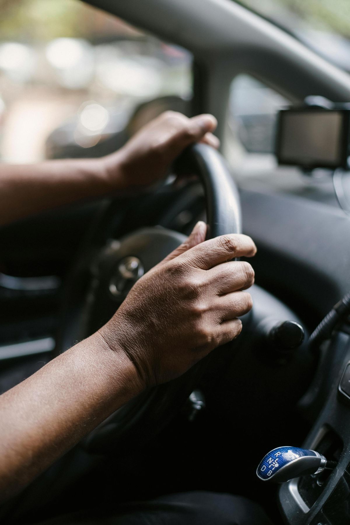 A driver's hands on the wheel during a daytime trip